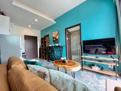 a living room with a couch and a flat screen tv at Rawai - Beachfront Apartement - The Title in Rawai Beach