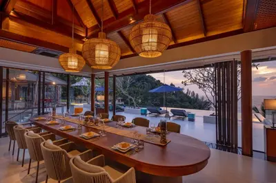 a dining room with a long table and chairs at Villa La Thale in Phuket Town