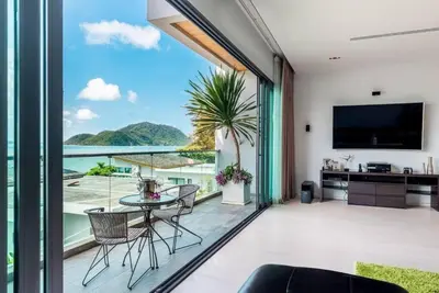 a living room with a table and chairs and a large window at EVA Beach sea view Four room villa in Ban Saiyuan (1)