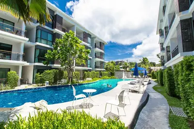 a swimming pool with chairs and a table in front of a building at The Title Boutique Phuket in Rawai Beach