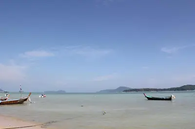 two boats sitting on the water on a beach at The Title Boutique Phuket in Rawai Beach