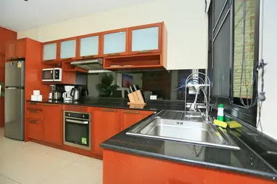 a kitchen with red cabinets and a sink in it at Rawai VIP 2D2 Tow-bedroom villa in Phuket Town