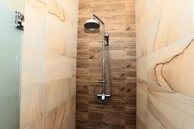 a shower in a bathroom with a wooden wall at Rawai VIP 2D2 Tow-bedroom villa in Phuket Town