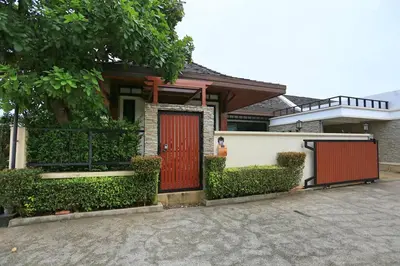a house with a red door and bushes at Rawai VIP 2D2 Tow-bedroom villa in Phuket Town