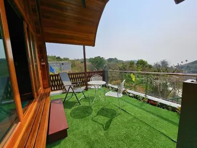 a balcony with a table and chairs on the grass at Seaview Eagles Nest Cabins in Rawai Beach