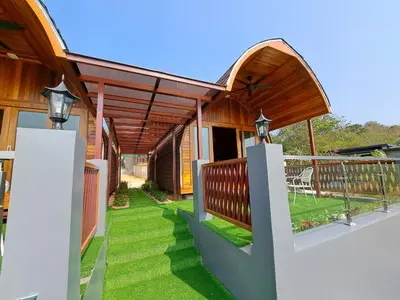 a house with a porch with green grass at Seaview Eagles Nest Cabins in Rawai Beach