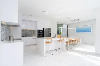 a kitchen with white cabinets and a table and chairs at Aesthetic 3 Storey Villa Residence A23, Private Pool, close to Ma Doo Bua Café and Laguna in Bang Tao Beach