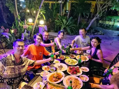 a group of people sitting around a table eating food at Charming Pool Twin Holiday Home in Patong Beach