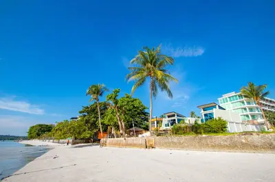 a beach with palm trees and buildings and the ocean at \u3010Beach Front\u3011\u6d77\u666f\u6c99\u6ee9\u522b\u5885\uff0c\u79c1\u4eba\u6cf3\u6c60\uff0c\u514d\u8d39\u65e9\u9910\uff0c\u5973\u4f63\u6bcf\u65e5\u6e05\u6d01\uff0c\u751f\u6d3b\u65b9\u4fbf\u4ea4\u901a\u4fbf\u5229 in Phuket Town
