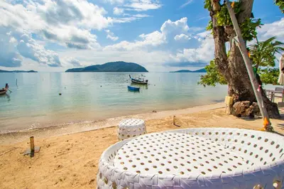 a white table and chairs on a beach at \u3010Beach Front\u3011\u6d77\u666f\u6c99\u6ee9\u522b\u5885\uff0c\u79c1\u4eba\u6cf3\u6c60\uff0c\u514d\u8d39\u65e9\u9910\uff0c\u5973\u4f63\u6bcf\u65e5\u6e05\u6d01\uff0c\u751f\u6d3b\u65b9\u4fbf\u4ea4\u901a\u4fbf\u5229 in Phuket Town