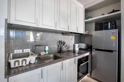a kitchen with white cabinets and a stainless steel refrigerator at \u3010Beach Front\u3011\u6d77\u666f\u6c99\u6ee9\u522b\u5885\uff0c\u79c1\u4eba\u6cf3\u6c60\uff0c\u514d\u8d39\u65e9\u9910\uff0c\u5973\u4f63\u6bcf\u65e5\u6e05\u6d01\uff0c\u751f\u6d3b\u65b9\u4fbf\u4ea4\u901a\u4fbf\u5229 B in Phuket Town
