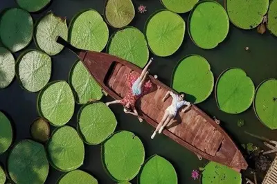 a person laying on a boat in the water with lilies at New Modern Aesthetic 3-Storey Villa A15 in Gated Residence just 10 min drive Laguna Phuket in Bang Tao Beach