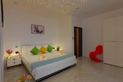 a bedroom with a bed and a red chair at Zen-Inspired Villa Retreat, Resort-Style Pool, Stunning Rooftop & Kid-Friendly Playground in Rawai Beach