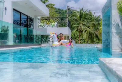 two girls sitting on a unicorn in a swimming pool at Zen-Inspired Villa Retreat, Resort-Style Pool, Stunning Rooftop & Kid-Friendly Playground in Rawai Beach