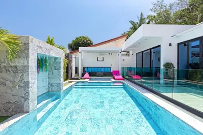 a swimming pool in the backyard of a house with pink chairs at Zen-Inspired Villa Retreat, Resort-Style Pool, Stunning Rooftop & Kid-Friendly Playground in Rawai Beach