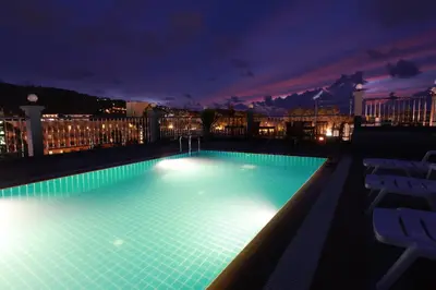 a large swimming pool with lights on a building at night at The Crystal Beach Hotel in Patong Beach