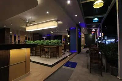 a restaurant with a bar and tables and chairs at The Crystal Beach Hotel in Patong Beach