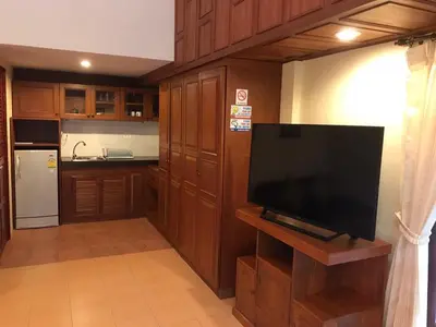 a kitchen with wooden cabinets and a flat screen tv at Bungalow Phuket in Kamala Beach