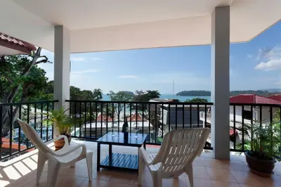 a balcony with a glass table and two chairs at Two Chefs Inn in Kata Beach