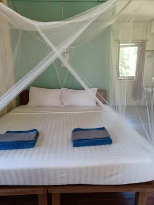 a white bed with two blue towels on it at Mangrove House Kohyao noi in Ban Bang Chak