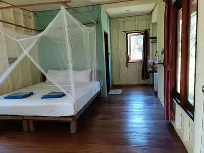 a bedroom with a bed with a mosquito net at Mangrove House Kohyao noi in Ban Bang Chak
