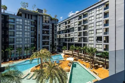 an apartment complex with a swimming pool and palm trees at Citygate Condo Kamala Phuket in Kamala Beach