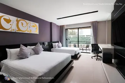 a hotel room with two beds and a desk at Beachfront Deluxe Infinity Pool in Patong Beach