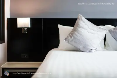 a bed with white pillows and a lamp on it at Beachfront Deluxe Infinity Pool in Patong Beach