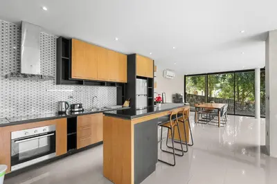 a kitchen with black and wooden cabinets and a table at Canary Villa - Kamala Beach in Kamala Beach