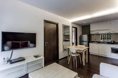 a kitchen with a table and a television on a wall at Cozy apartment at The Title Rawai by Lofty in Rawai Beach