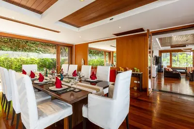a dining room with a table and white chairs at Seaview Villa Yang Som at Surin Beach in Thalang