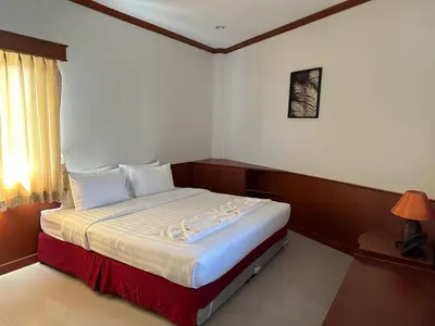 a bedroom with a bed with white sheets and a window at Sabai Sabai hotel in Kata Beach