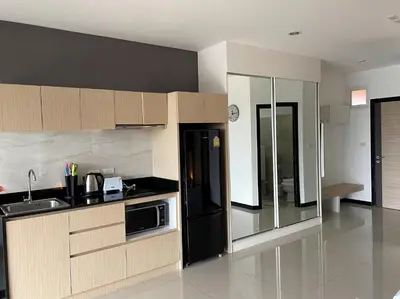 a kitchen with wooden cabinets and a black refrigerator at Nai Harn spacious studio great amenities in Rawai Beach