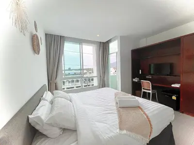 a bedroom with a large white bed and a desk at Chalong Inn Phuket in Ban Klang