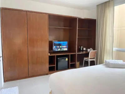 a bedroom with a bed and a tv and a cabinet at Chalong Inn Phuket in Ban Klang