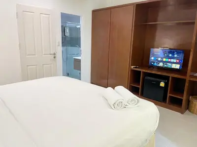 a bedroom with a white bed with towels on it at Chalong Inn Phuket in Ban Klang