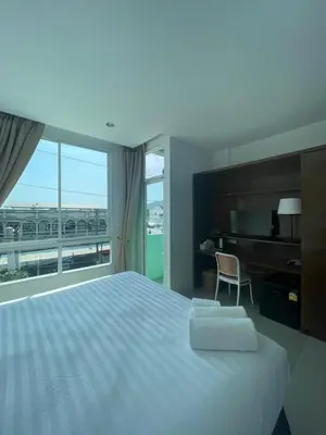 a bedroom with a large bed and a large window at Chalong Inn Phuket in Ban Klang