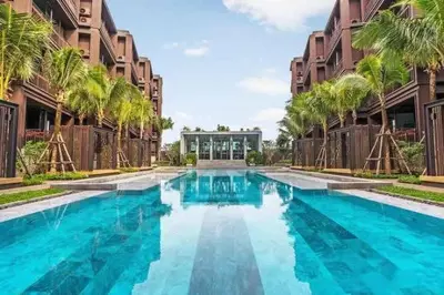 a swimming pool with palm trees and a building at Saturdays Residence By JJM in Ban Saiyuan (1)