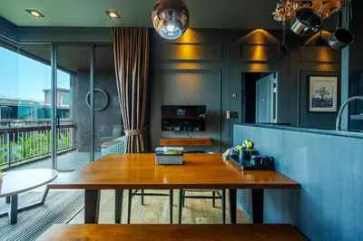a dining room with a wooden table on a balcony at Saturdays Residence By JJM in Ban Saiyuan (1)