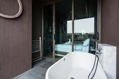 a bathroom with a bath tub and a bedroom at Saturdays Residence By JJM in Ban Saiyuan (1)
