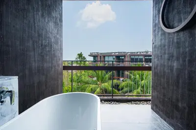 a bathroom with a tub and a view of a building at Saturdays Residence By JJM in Ban Saiyuan (1)