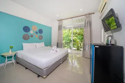 a bedroom with a bed and a flat screen tv at Kata Sea Boutique in Kata Beach
