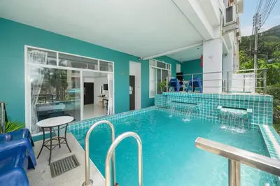 a swimming pool with a table and chairs next to a building at Kata Sea Boutique in Kata Beach