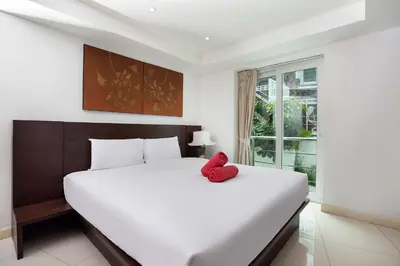 a white bed with a red stuffed animal on it at Kata SeaView 2BR Apartment M12, just 5 min Drive from Kata Beach in Kata Beach