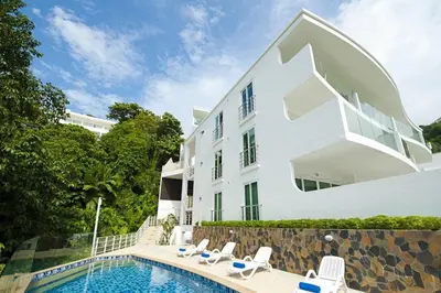 a white building with a swimming pool next to a house at Kata SeaView 2BR Apartment M12, just 5 min Drive from Kata Beach in Kata Beach
