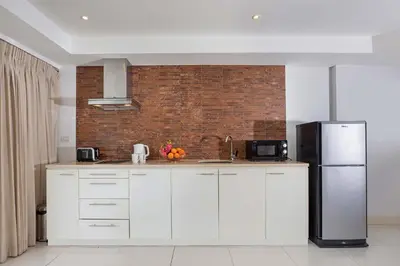 a kitchen with white cabinets and a black refrigerator at Kata SeaView 2BR Apartment M12, just 5 min Drive from Kata Beach in Kata Beach