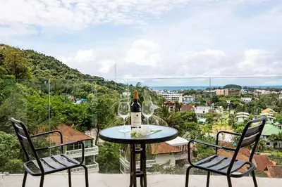 a table with a bottle of wine and two chairs at Kata SeaView 2BR Apartment M12, just 5 min Drive from Kata Beach in Kata Beach