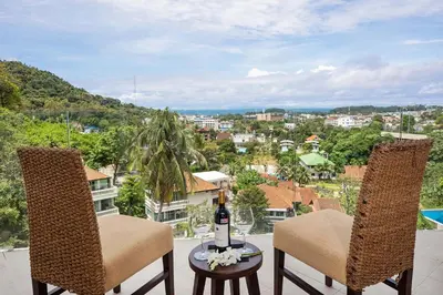 a balcony with two chairs and a table with a bottle of wine at Kata SeaView 2BR Apartment M12, just 5 min Drive from Kata Beach in Kata Beach