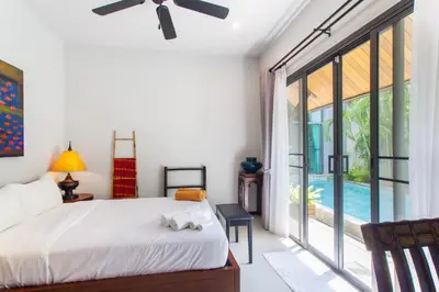 a bedroom with a bed and a large window at Stylish 3BR Pool Villa Onyx H4, Gated Residence, Near Rawai & Naiharn Beach in Rawai Beach