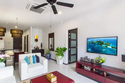 a living room with a white couch and a flat screen tv at Stylish 3BR Pool Villa Onyx H4, Gated Residence, Near Rawai & Naiharn Beach in Rawai Beach